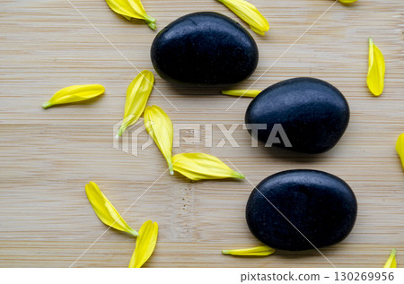 Three zen stones with scattered yellow petals arranged on wood clean look with customizable space for text Three zen stones with scattered yellow petals arranged on wood clean look with customizable space for text 130269956