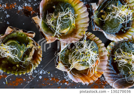 Delicious grilled scallops in shells, fresh seafood with a sause and soy sprouts. 130270036