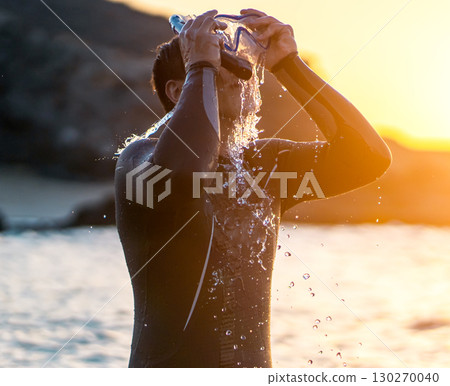 A man is preparing for diving in the ocean at sunset. A man is preparing for diving in the ocean at sunset. 130270040