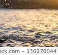 Drops of water fallling to the ocean at sunset closeup. 130270044