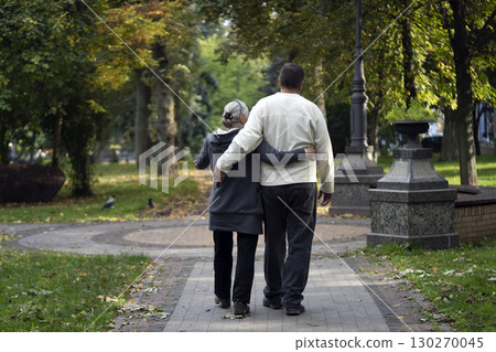 An elderly couple, man and woman walk in the autumn park. An elderly couple, man and woman walk in the autumn park. 130270045