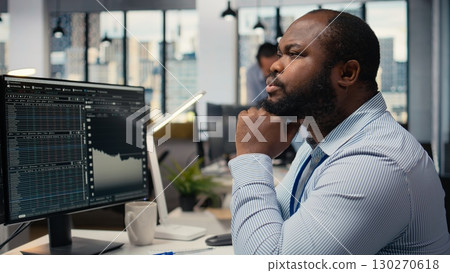 Close up of trader daydreaming, visualizing becoming rich after stock market speculations. African american man in prop firm office lost in thought, picturing prosperous trade Close up of trader daydreaming, visualizing becoming rich after stock market speculations. African american man in prop firm office lost in thought, picturing prosperous trade 130270618