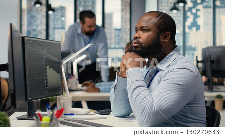Day trader analyzes stock market price charts, doing thinking, making buy and sell decisions in prop firm office. Man doing brainstorming, placing client orders using trading platform Day trader analyzes stock market price charts, doing thinking, making buy and sell decisions in prop firm office. Man doing brainstorming, placing client orders using trading platform 130270633