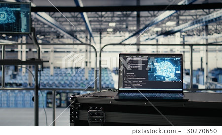 Artificial intelligence technology on notebook in industrial data center facility helping power internet services. AI coding script running on laptop in server farm built for digital storage systems 130270650