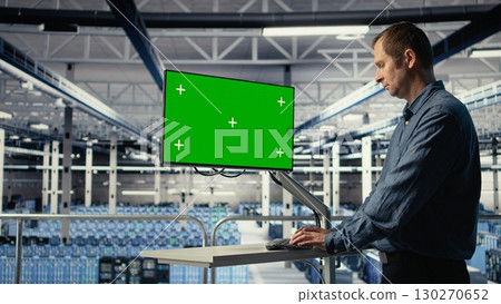 IT expert monitors server farm activity using green screen workstation. Data center system administrator reviews rigs tests results on mockup display to ensure systems are working correctly, camera A 130270652