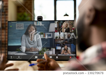 Black businessman leads virtual discussion with investors and shareholders during teleconference in brick wall room. Company advisor manages remote meeting from modern home office setup. Black businessman leads virtual discussion with investors and shareholders during teleconference in brick wall room. Company advisor manages remote meeting from modern home office setup. 130270678