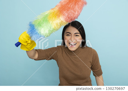 Young asian housekeeper with smile on face, excitedly holding feather duster, ready to tackle chores. Enthusiastic female cleaner prepared for professional household cleaning tasks. Young asian housekeeper with smile on face, excitedly holding feather duster, ready to tackle chores. Enthusiastic female cleaner prepared for professional household cleaning tasks. 130270697
