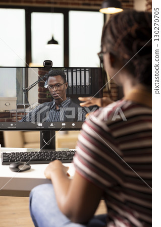 African american woman uses computer for virtual meeting, discussing company marketing strategies with businessman. Black colleagues connect remotely in video call during focused work session. 130270705