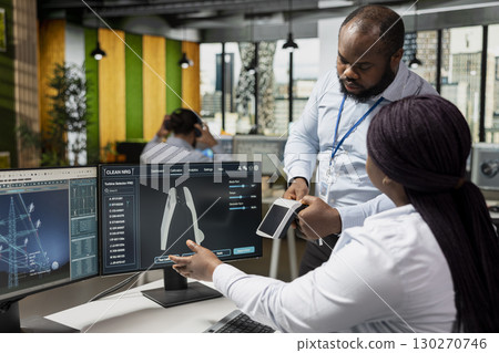 Green technology company engineering team working on innovative sustainability projects in office, integrating solar energy products with advanced electric grid solutions. 130270746