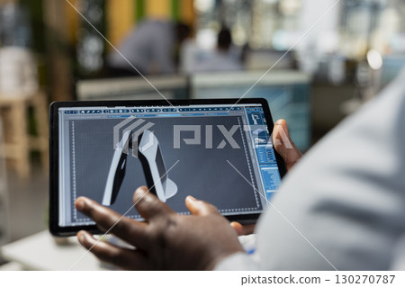 Close up of product designer in office using digital tablet to creating compact solar gadget. Engineer uses touchscreen device to design solar gadget prototype, reducing carbon footprint 130270787