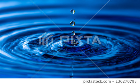 A close-up shot shows water droplets falling into a body of water, creating concentric ripples on the surface. Water droplet impact showing ripple effect and reflection in the water surface. A close-up shot shows water droplets falling into a body of water, creating concentric ripples on the surface. Water droplet impact showing ripple effect and reflection in the water surface. 130270793