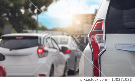 Close up of a car tail light in a traffic jam. With a blurred background. Sunlight creates a lens flare capturing the feeling of being stuck. Many cars are parked in a row. 130271028