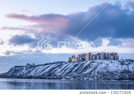 Residential neighborhood on the banks of the Yenisei River on a frosty winter evening, Krasnoyarsk, Russia. A Beautiful Winter Landscape featuring Snowy Hills harmoniously alongside Modern Buildings 130271926
