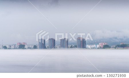 In a tranquil morning setting, fog blankets the residential neighborhood along the Yenisei River in Krasnoyarsk. 130271930
