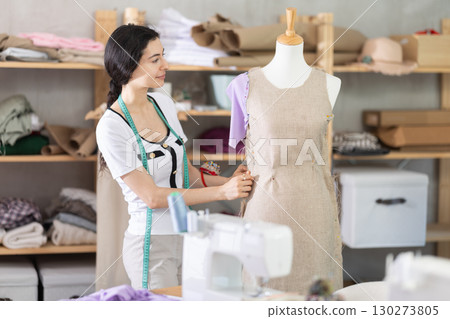 Fashion designer fitting dress on mannequin in dressmaker studio 130273805