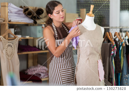 Female fashion designer working with mannequin and sewing fabric 130273828