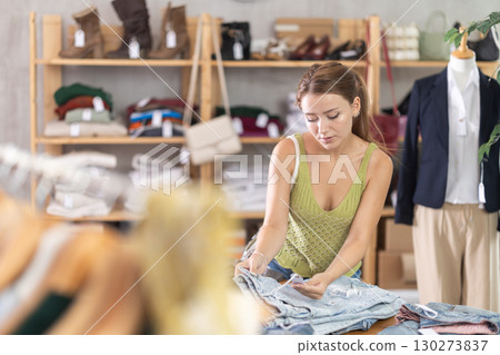 Young woman standing choosing pants in store Young woman standing choosing pants in store 130273837