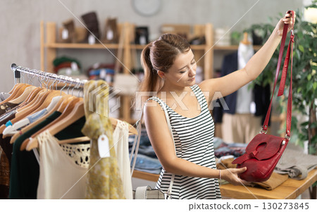 Young girl shopping - choosing a fashionable handbag in clothing store Young girl shopping - choosing a fashionable handbag in clothing store 130273845