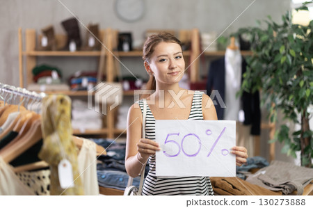 Portrait of young girl holding sign saying 50 percent discount in clothing store Portrait of young girl holding sign saying 50 percent discount in clothing store 130273888
