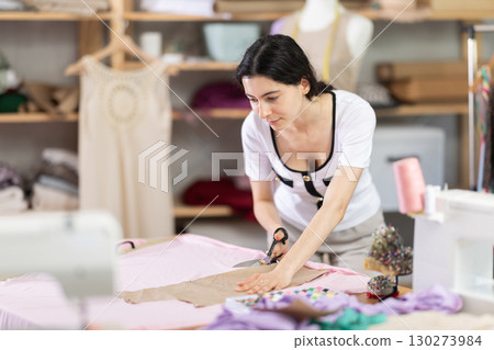 Woman standing near table and cutting fabric Woman standing near table and cutting fabric 130273984