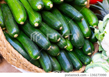 Bunch of ripe green zucchinis in wicker basket 130273990