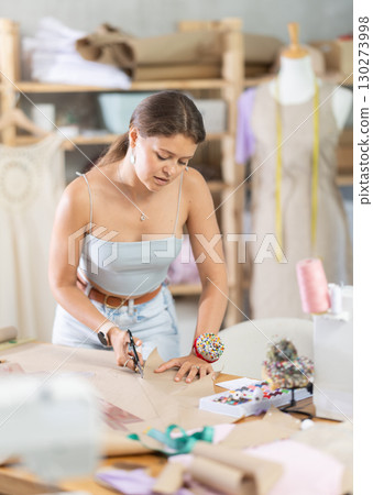 Female fashion maker cutting paper pattern for bespoke garment Female fashion maker cutting paper pattern for bespoke garment 130273998