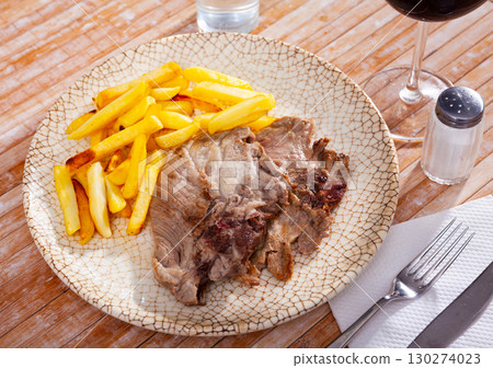 Pork chop with French fries on a plate. 130274023