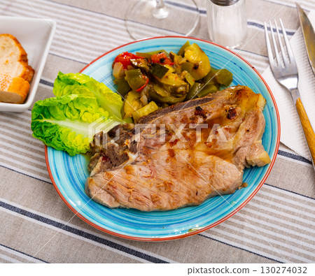 Juicy roast pork on a plate with stewed vegetables 130274032