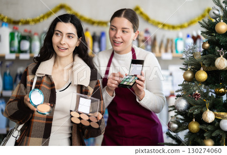 Girl consultant helps female buyer choose eye shadow set Girl consultant helps female buyer choose eye shadow set 130274060