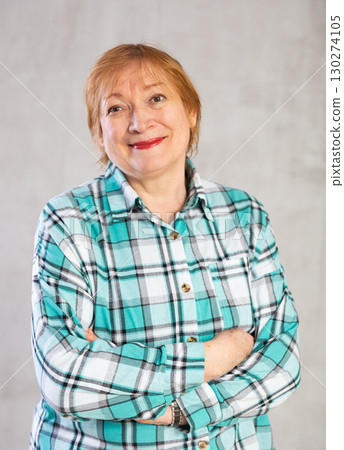 Smiling aged woman in plaid shirt standing with arms crossed 130274105