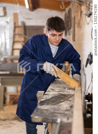 Young guy working with wooden board on workbench 130274190