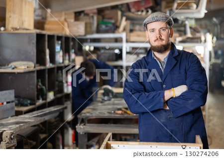 Young man carpenter posing in wood workshop Young man carpenter posing in wood workshop 130274206