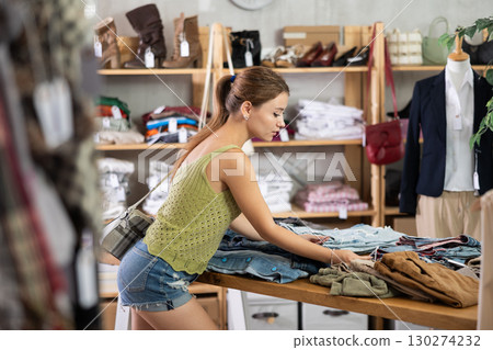 Young woman standing choosing pants in store 130274232