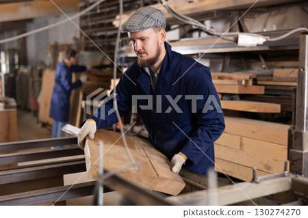 Young man putting wooden board on cutting machine 130274270