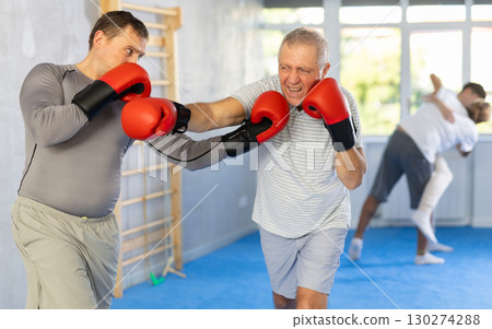 Men in boxing gloves punch deliver blow each other during training sparring session. 130274288