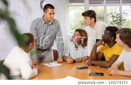 Team leader giving instructions to group of men during work meeting 130274351