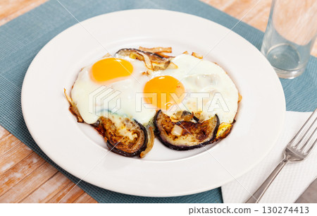 Fried sunny side up eggs with eggplant and onions 130274413