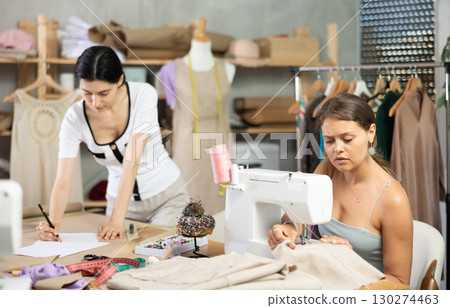 Female dressmakers working together in a sewing workshop Female dressmakers working together in a sewing workshop 130274463