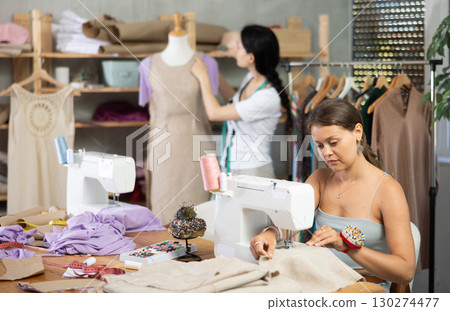 Dressmakers work in the workshop and sew clothes Dressmakers work in the workshop and sew clothes 130274477