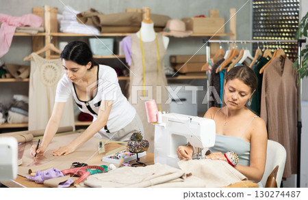 Two female tailors working on custom garment in studio 130274487