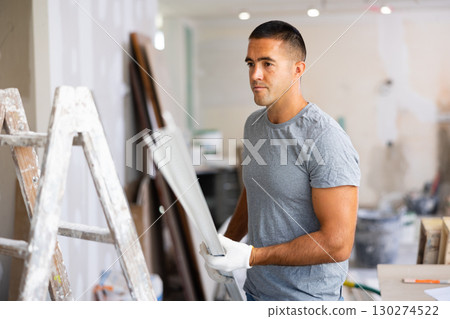 Young man holds an aluminum profile for interior decoration 130274522