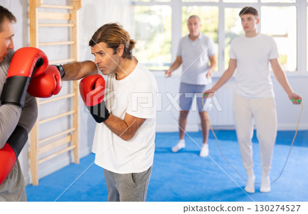 Men in boxing gloves punch deliver blow each other during training sparring session. Men in boxing gloves punch deliver blow each other during training sparring session. 130274527