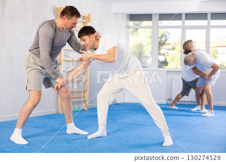 Young guy and man practice wrestling, apply techniques of Aikido and self-defense. 130274529