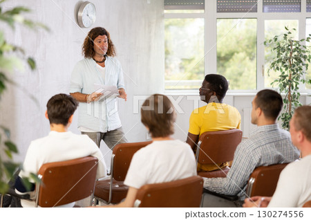 Man lecturing to group of men gathered in study hall 130274556