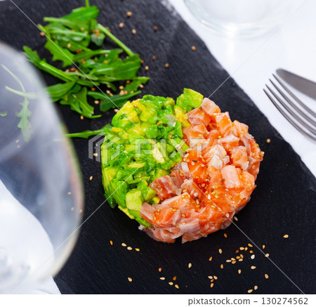 Salmon tartare with avocado garnished with greens on slate board 130274562
