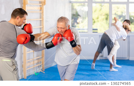 Men in boxing gloves punch deliver blow each other during training sparring session. 130274565