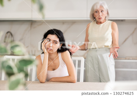 Elderly woman quarreling with young woman in kitchen Elderly woman quarreling with young woman in kitchen 130274625