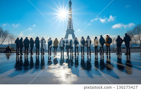 Silhouetted figures reflected in water with tall tower background 130275427