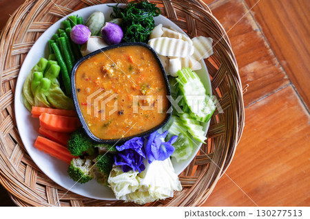 A hand is dipping Chili paste with fresh vegetables, asain cuisine A hand is dipping Chili paste with fresh vegetables, asain cuisine 130277513