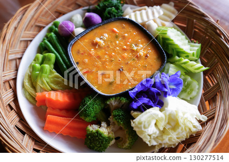 A hand is dipping Chili paste with fresh vegetables, asain cuisine 130277514
